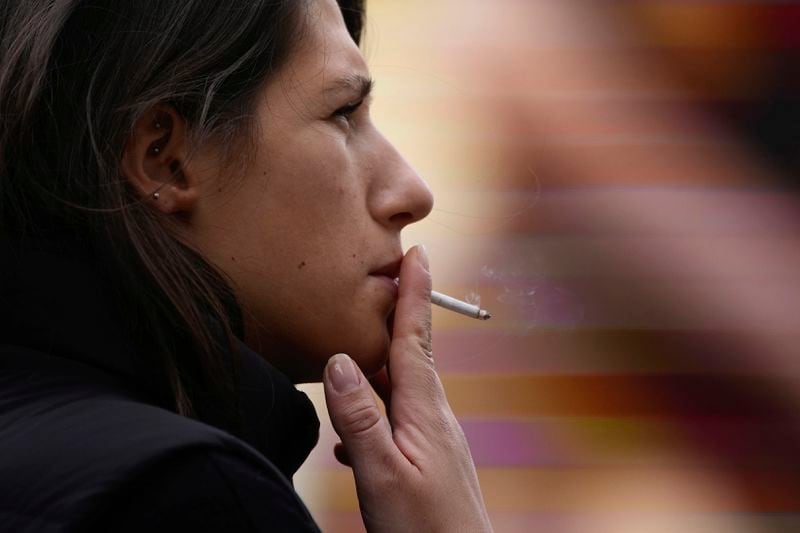 A woman smokes on a street, in London, Tuesday, April 16, 2024. A bold plan to ban anyone born after 2008 from ever legally buying cigarettes in Britain faces its first test in Parliament. The bold plan has divided the governing Conservatives, with some hailing its public health benefits and others condemning it as state overreach. (AP Photo/Kin Cheung)