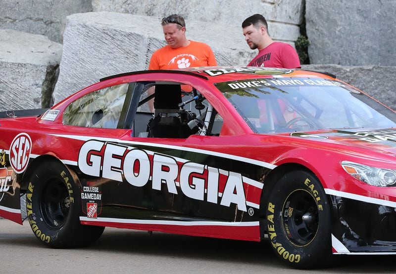 A Clemson fan and a Georgia fan take in the NASCAR stock car of Chase Elliott decorated at the College Gameday Tail Gate for the top-5 matchup between No. 3 Clemson and No. 5 Georgia in the Duke’s Mayo Classic on Sept. 3, 2021, in Charlotte. (Curtis Compton / Curtis.Compton@ajc.com)