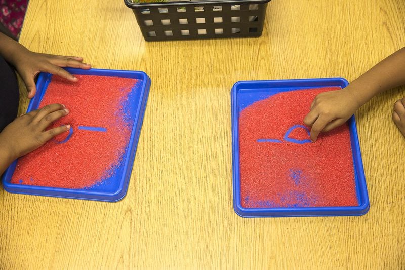Kindergartners draw the letter “b” in a tray of sand while learning phonics at Benteen Elementary School in Atlanta. 