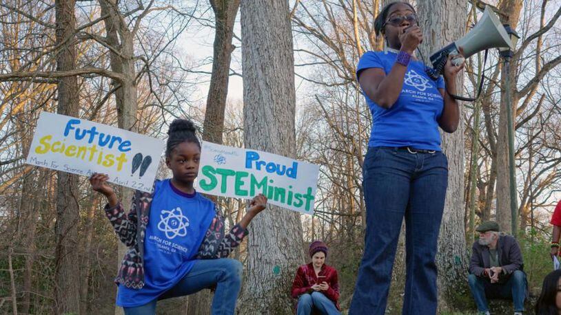 Dr. Jasmine Clark, a microbiologist who organized the Atlanta March for Science, promoted the Earth Day march at a women’s rally on March 8 at Candler Park. Her 8-year-old daughter, Jayda, held signs nearby.