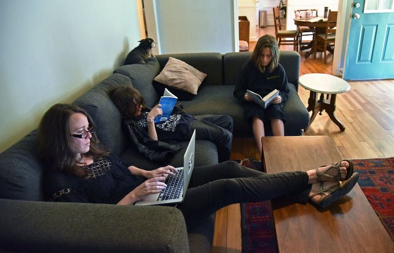 Children’s author Laurel Snyder works on her emails as her sons Lewis, 10, and Mose (right), 11, read books at their home in Ormewood Park recently. HYOSUB SHIN / HSHIN@AJC.COM