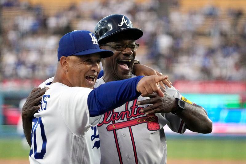 Los Angeles Dodgers manager Dave Roberts, left, and Atlanta Braves third base coach Ron Washington acknowledge someone in the crowd prior to a baseball game Thursday, Aug. 31, 2023, in Los Angeles. (AP Photo/Mark J. Terrill)