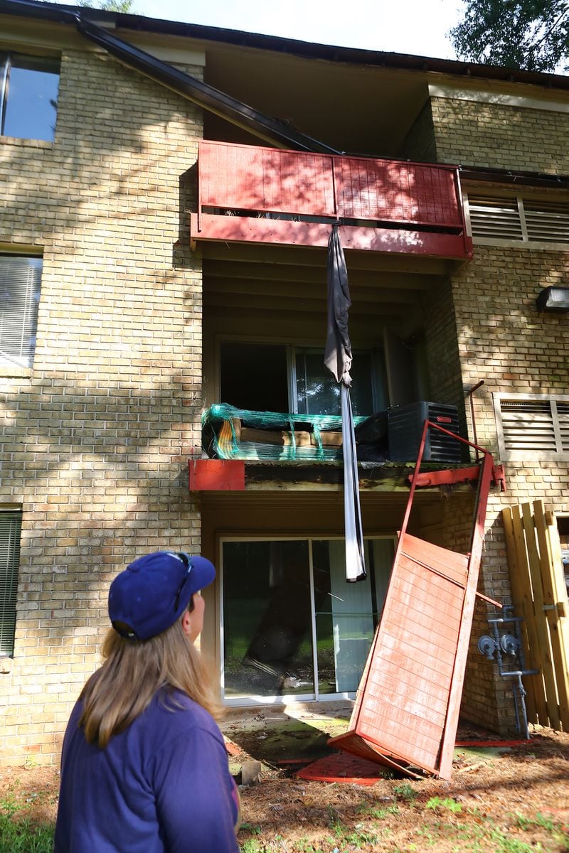 On the back side of Kristy Neff’s row of apartments at The Village at Kensington, a gutter has collapsed and a balcony railing hangs off the building. Neff called her own apartment unit “a death trap.” (Curtis Compton / Curtis.Compton@ajc.com)