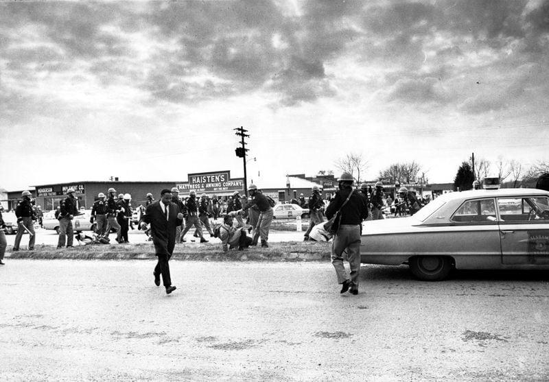 In this March 7, 1965, file photo, march leader Hosea Williams, left, leaves the scene as state troopers break up the civil rights voter registration march in Selma, Ala., and put John Lewis, center, of the Student Non-violent Coordinating Committee on the ground. Hundreds gathered Sunday, March 3, 2013 for a brunch with Vice President Joe Biden, and thousands were expected Sunday afternoon to march across this bridge in Selma's annual Bridge Crossing Jubilee. The event commemorates the "Bloody Sunday" beating of voting rights marchers by state troopers as they began a march to Montgomery in March 1965. The 50-mile march prompted Congress to pass the Voting Rights Act that struck down impediments to voting by African-Americans and ended all-white rule in the South. (AP Photo/File)