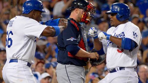 Los Angeles Dodgers' Juan Uribe, right, greets Dodgers' Yasiel Puig, left, at the plate next to Atlanta Braves catcher Brian McCann, center, after Uribe hit a two-run home run to score Puig in the fourth inning in Game 3 of the National League division baseball series Sunday, Oct. 6, 2013, in Los Angeles. (AP Photo/Mark J. Terrill)