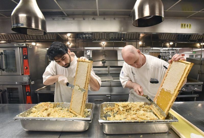 Adam Sheff (left), executive sous chef, and James Gallo, pastry chef, prepare hive frames before they insert them into the honey extractor at Hyatt Regency Atlanta. HYOSUB SHIN / HYOSUB.SHIN@AJC.COM