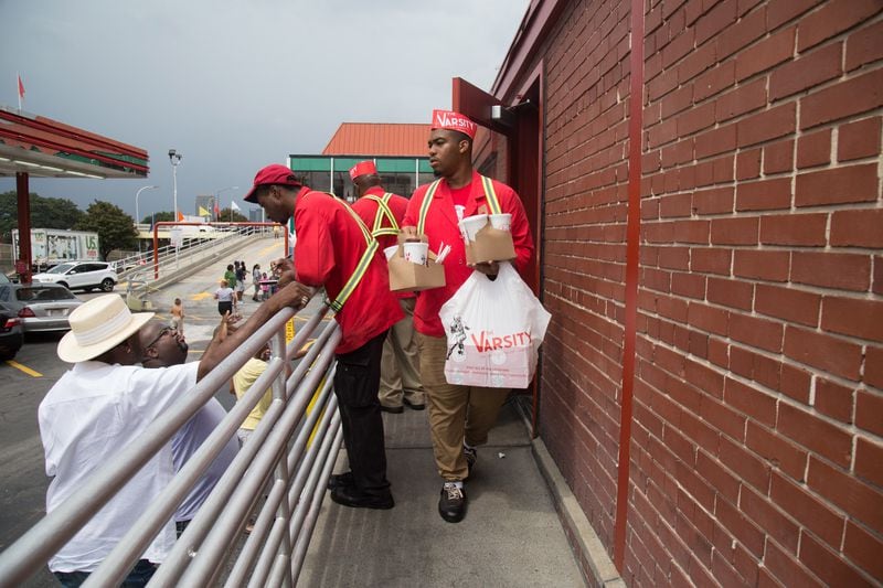 Server David Corbett looks for his customer to deliver his food during the Varsity’s 90th birthday party on Saturday, August 18, 2018, in Atlanta. Hundreds of people turned out at the landmark restaurant, where all menu items were 90 cents in honor of the birthday. (Photo: STEVE SCHAEFER / SPECIAL TO THE AJC)