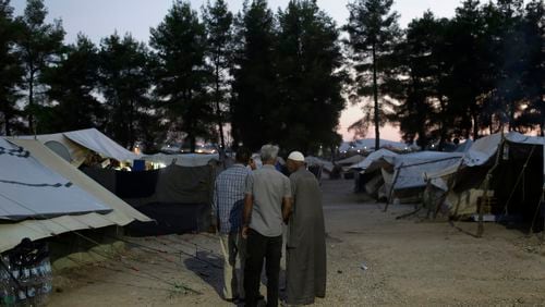 In this photo taken on Tuesday, Sept. 13, 2016 photo, Syrian men walk among tents at Ritsona refugee camp north of Athens. Most of the people at the camp arrived in Greece in March, crossing to Lesbos and Chios just ahead of an agreement between the EU and Turkey that took effect. Under the deal, anyone arriving on Greek islands from Turkey on or after March 20 would be held on the island and face being returned to Turkey. Balkan countries began restricting crossings of their borders in early 2016, and shut them completely in early March, stranding tens of thousands of people in Greece. (AP Photo/Petros Giannakouris)