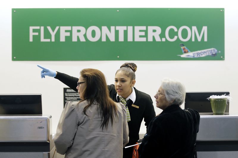 FILE - In this Oct. 15, 2014 file photo, a Frontier Airlines employee directs passengers at Cleveland Hopkins International Airport in Cleveland. There are few businesses that consumers love to hate more than airlines, but travelers seem to reserve a special level of vitriol for the no-frills, discount airlines. (AP Photo/Tony Dejak, File)