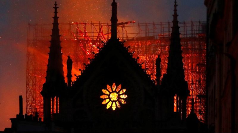 Flames and smoke rise from Notre Dame cathedral as it burns in Paris, Monday, April 15, 2019. Massive plumes of yellow brown smoke is filling the air above Notre Dame Cathedral and ash is falling on tourists and others around the island that marks the center of Paris.  