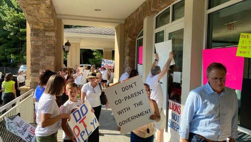 People opposed to Fulton County Schools' mask mandate protest outside a board meeting on Aug. 13, 2021. VANESSA McCRAY/AJC FILE PHOTO