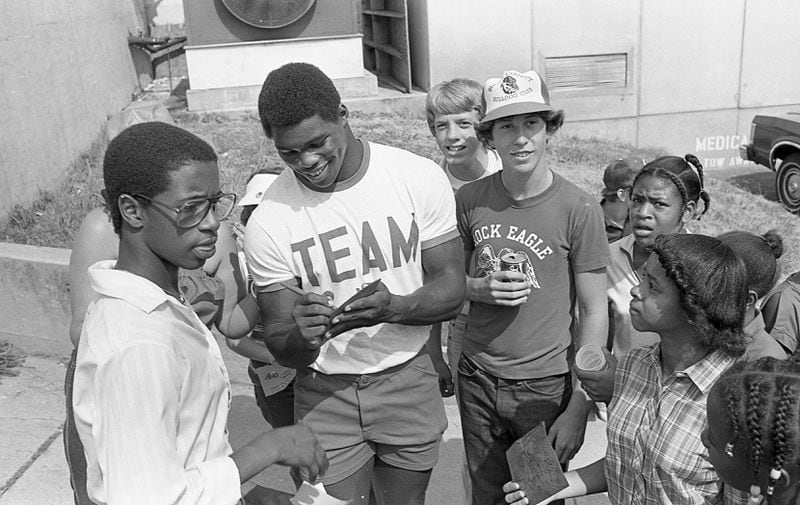 Georgia's Herschel Walker wears a 'TEAM' t-shirt while signing autographs for fans after another win in Athens in 1980. AJC file photo