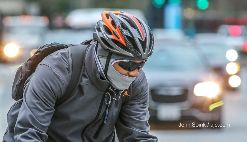 Chris Alexander bundled up on Peachtree Road in Buckhead as he rode his bike on the first full day of spring. JOHN SPINK / JSPINK@AJC.COM