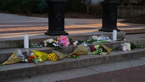 Flowers and candles left under The Arch at the University of Georgia in memory of Laken Riley, who was killed Feb. 22 on the running trails behind Lake Herrick in Athens, GA, Monday, February 26, 2024.  (Nell Carroll for The Atlanta Journal-Constitution)