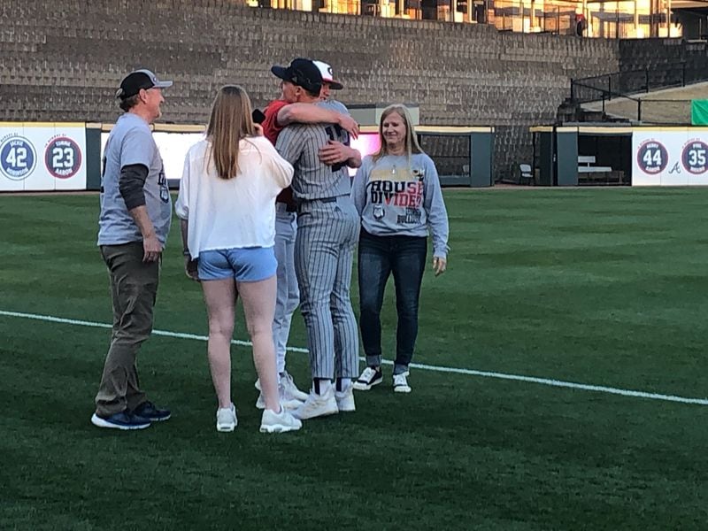 In the company of their parents Mitch and Beth and sister Kyra, Georgia Tech pitcher Jackson Finley (gray uniform) and brother Leighton, a Georgia pitcher, exchange a hug after both competed in the Yellow Jackets' 4-1 win over the Bulldogs on Sunday at Coolray FIeld in Lawrenceville. (AJC photo by Ken Sugiura)