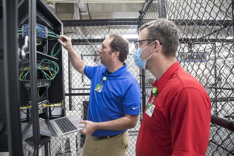Floyd Medical Center network engineers Daniel Wilson (right) and Kevin Prewett (left) configure the network inside of a newly constructed pop-up hospital located in the parking garage at Floyd Medical Center in Rome,. (ALYSSA POINTER / ALYSSA.POINTER@AJC.COM)