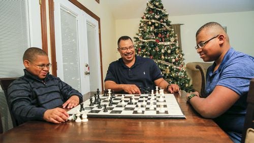 Corey McDaniel (middle) coaches his sons Corey Jr. (right), 14, and Christian, 11, in a game of chess at their Stone Mountain home this week. Corey, a single dad, lost his wife, Allison McDaniel, when she died suddenly after suffering complications from a seizure in 2016. ALYSSA POINTER / ALYSSA.POINTER@AJC.COM
