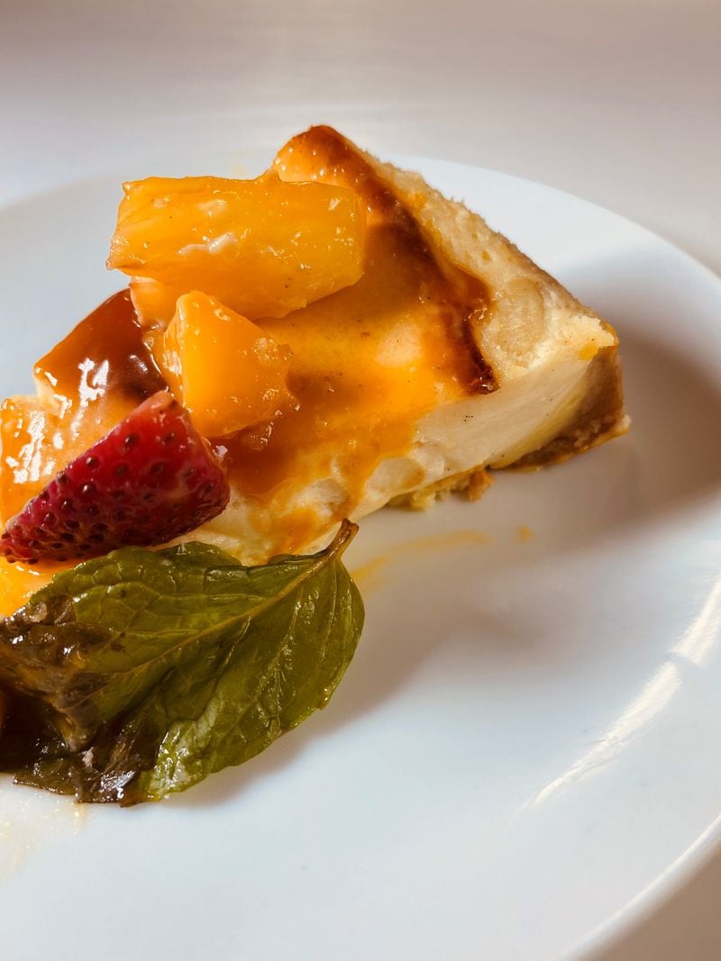 Creme brulee cheesecake comes with freshly sliced fruit and mango drizzle at Taffer’s Tavern. Bob Townsend for The Atlanta Journal-Constitution 