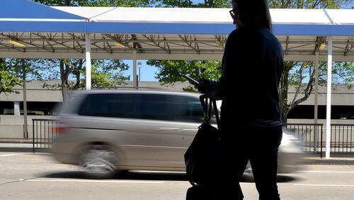 An arriving passenger waits for a ride at Hartsfield Jackson International Airport. According to a recent Morgan Stanley report, ride-sharing services could disrupt transit planning as much as they're already disrupting taxi services. (Brant Sanderlin / AJC file)