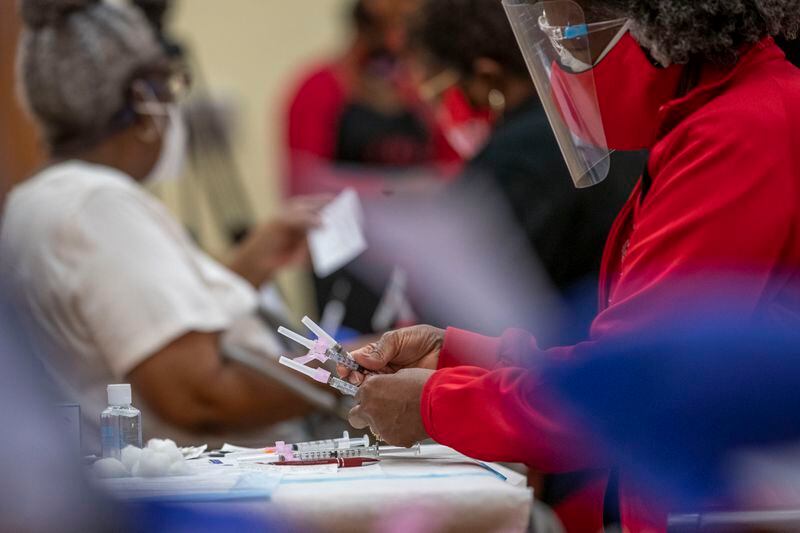 A DeKalb County Board of Health medical worker handles unused COVID-19 syringes during a vaccination event at the Lou Walker Senior Center in Stonecrest organized by the DeKalb County Board of Health and Delta Sigma Theta Sorority in early February. (Alyssa Pointer / Alyssa.Pointer@ajc.com)