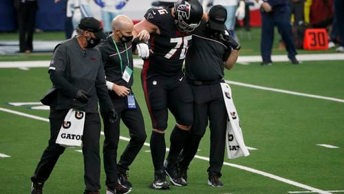 Falcons offensive guard Kaleb McGary (76) is helped off the field after suffering a knee injury during the first half Sunday, Sept. 20, 2020, against the Dallas Cowboys in Arlington, Texas. (Michael Ainsworth/AP)