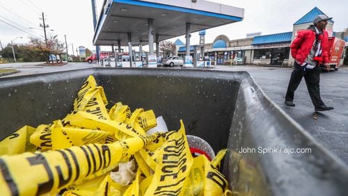 Discarded crime scene tape sits at a Chevron gas station on the corner of Pryor Road and University Avenue in southwest Atlanta, where three people were shot Wednesday night.