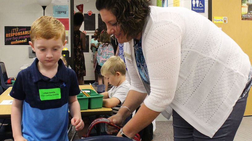 Emily Costine, a kindergarten teacher at Level Creek Elementary School, helps her student, Leland Griffin, get in his seat during the first day of school at Level Creek Elementary School on August 6, 2020. Costine teaches one of the dual language immersion classes. Gwinnett County Public Schools is offering signing bonuses to bilingual teachers. Jenna Eason / Jenna.Eason@coxinc.com