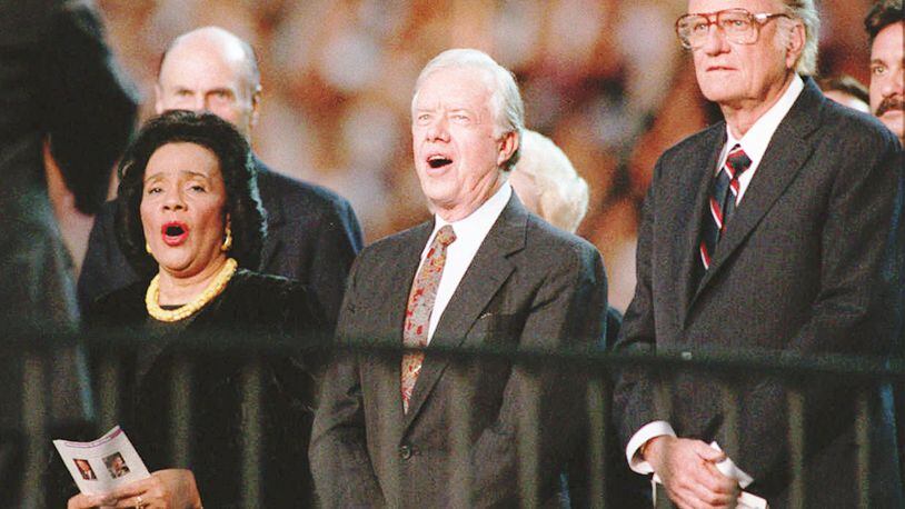from left Coretta Scott King former President Jimmy Carter and Billy Graham stand and sing Blessed Assurance All Hail the Power at the Atlanta Billy Graham Crusade at the Georgia Dome Wednesday night About 49 800 people showed for the crusade on its first night in Atlanta Frank Niemeir Staff