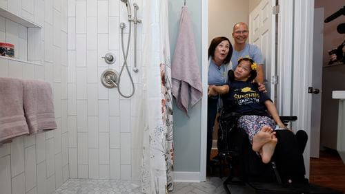 Christy Clayton (left) and her husband Greg (right) get the first glimpse of their daughter Celia’s bathroom after a renovation by Sunshine on A Ranney Day on Monday, November 21, 2022. The organization does home renovations for handicapped and disabled children. (Natrice Miller/natrice.miller@ajc.com)  