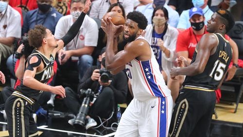 Joel Embiid grabs a rebound against Trae Young and Clint Capela during the first half of Monday's Game 4 of the Eastern Conference semifinals.