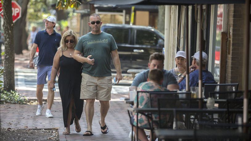 A couple walks past the Six Pence restaurant on Bull Street in the Historic Downtown Savannah. Savannah became the first major city in Georgia to require the use of face masks, setting up a potential showdown with Gov. Brian Kemp over whether local officials can take more sweeping steps than the state to contain the coronavirus. (AJC Photo/Stephen B. Morton)