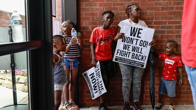 Shalonda holds a “we won’t go,, we will fight back” sign alongside her nieces and nephews as tenants of Forest at Columbia Apartments demand to speak to a commissioner inside of the DeKalb Government Building on Thursday, July 28, 2022. (Natrice Miller/natrice.miller@ajc.com)
