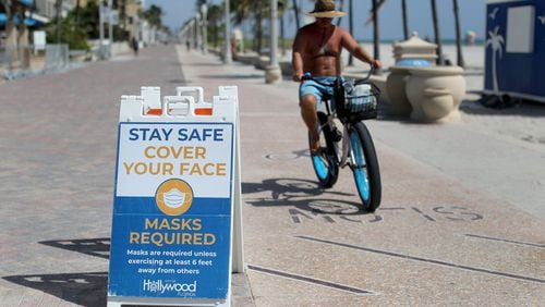 Signs posted along the broadwalk on the beach in Hollywood Florida advocate for people to wear a mask unless exercising 6 feet away from others in September 2020. (Mike Stocker/South Florida Sun Sentinel/TNS)