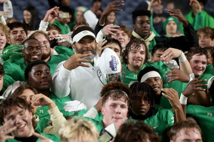 Buford head coach Bryant Appling, center, and players hold up three fingers after their third state championship in a row after their 21-20 win against Langston Hughes in the Class 6A state title football game at Georgia State Center Parc Stadium Friday, December 10, 2021, Atlanta. JASON GETZ FOR THE ATLANTA JOURNAL-CONSTITUTION