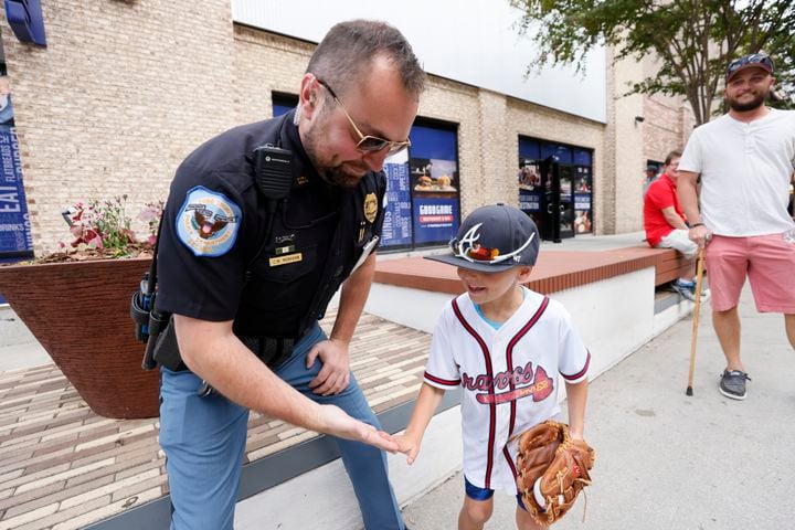 Cobb County Detective Clint Monahan gives a high five to Corbin Garab outside of the Truist Park on Tuesday, October, 11 2022. The Braves face the Phillies for the first game of the  National League Division Series. 
