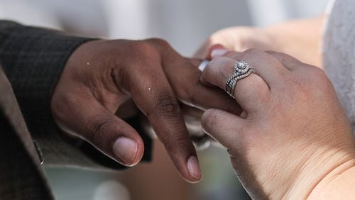 File Photo: A bride slides a ring onto the finger of her groom. Damon Higgins / The Palm Beach Post