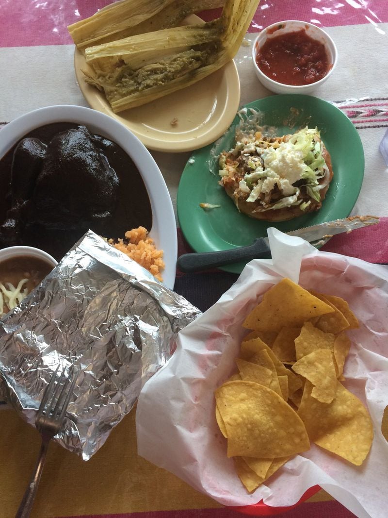 A Mexican spread at Taqueria La Oaxaqueña in Jonesboro includes (clockwise from left) chicken mole, a pork tamale in green-chile salsa; a sope with lengua; chips and salsa. CONTRIBUTED BY WENDELL BROCK
