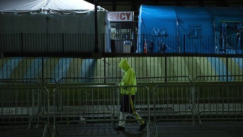 A man walks by the triage tents outside of Elmhurst Hospital in New York on March 26, 2020. (AP Photo/Marshall Ritzel)