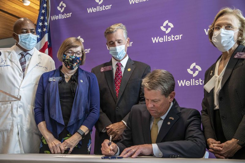 Gov. Brian Kemp signs a bill into law Thursday at the new building for Wellstar Kennestone Hospital's emergency department in Marietta. Kemp signed several bills involving medical care and health care coverage during his visit to the facility. (ALYSSA POINTER / ALYSSA.POINTER@AJC.COM)