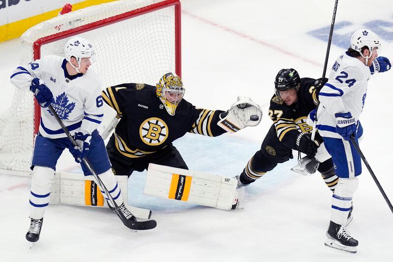 Boston Bruins' Jeremy Swayman (1) makes a glove save behind Toronto Maple Leafs' David Kampf (64) as Hampus Lindholm (27) defends against Toronto Maple Leafs' Connor Dewar (24) during the first period of Game 7 of an NHL hockey Stanley Cup first-round playoff series, Saturday, May 4, 2024, in Boston. (AP Photo/Michael Dwyer)