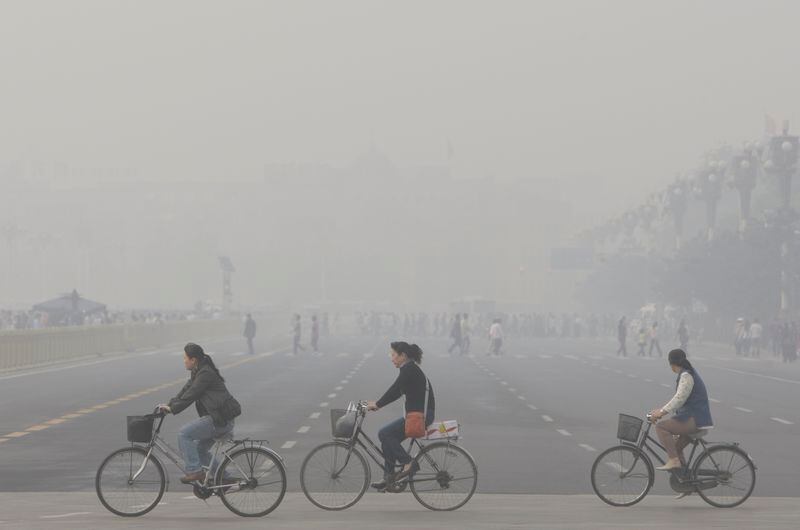 Chinese women cycling through smog and pollution over Beijing's Tiananmen Square in 2008. (AP Photo/Oded Balilty, File)