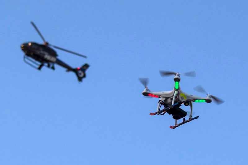 A police helicopter flies past a UAV drone which was flying over a post-march street celebration in west Baltimore, Maryland, in this file photo taken May 2, 2015. The Federal Aviation Administration announced industry partnerships on Wednesday to test commercial drones that can fly beyond an operator's line of sight, seen as a necessary precursor to autonomous drone operations such as package delivery. REUTERS/Adrees Latif/Files