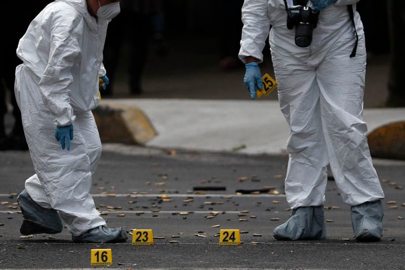Forensic investigators tag cartridges at the scene where the Mexican capital's police chief was attacked by gunmen.