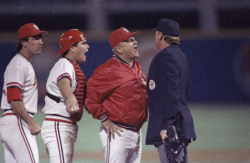 FILE - St. Louis Cardinals manager Whitey Herzog lets umpire John Shulock, right, know how he feels about Shulock's call on the tag attempt on Kansas City Royals Jim Sundberg by Cardinals catcher Tom Nieto, second from left, in the second inning of Game 5 of the World Series in St. Louis, Mo., Oct. 24, 1985. Shulock had ruled Sundberg safe on the play. The Cardinal player at far left is unidentified.Herzog, the gruff and ingenious Hall of Fame manager who guided the St. Louis Cardinals to three pennants and a World Series title in the 1980s and perfected an intricate, nail-biting strategy known as "Whiteyball," has died. He was 92. Cardinals spokesman Brian Bartow said Tuesday, April 16, 2024, the team had been informed of his death by Herzog's family. (AP Photo/Peter Southwick, File)