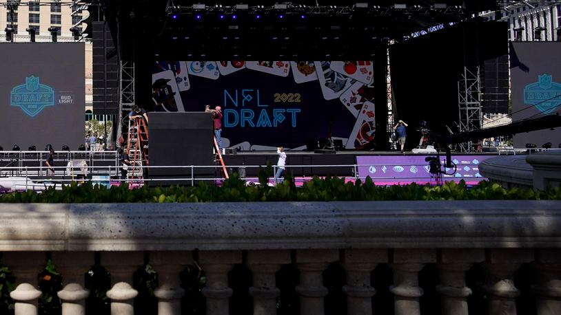 People look on as workers erect a stage during setup for the NFL draft Tuesday, April 26, 2022, in Las Vegas. (AP Photo/John Locher)