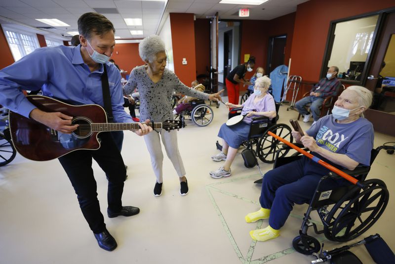 John Abel, music director at A.G. Rhodes Nursing Home, performs during a music therapy class as resident Barbara Walker dances. Virginia Beaty, right, and Shelia Lindsey, play instruments. 
“So complacency is the word we do not want. We have just only just started to breathe again at the nursing home again,” Cateau said.
Miguel Martinez / miguel.martinezjimenez@ajc.com