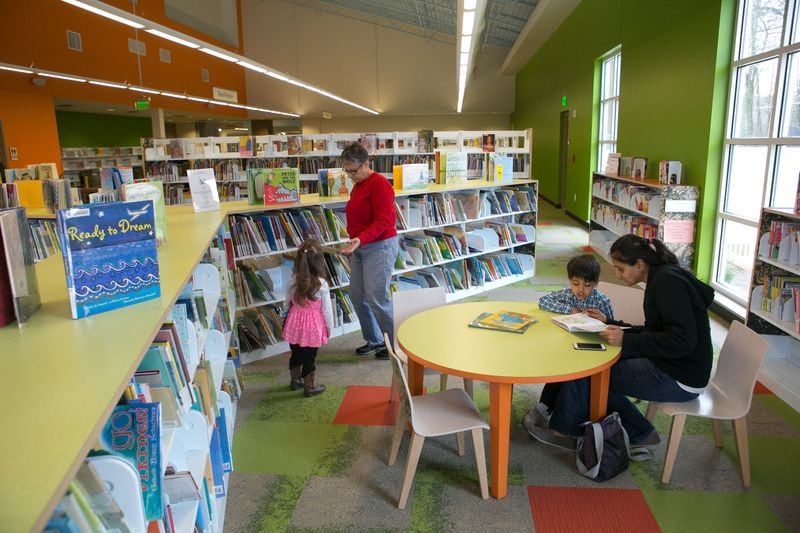 In this file photo from last year, Margarita Sleeper of Roswell and her granddaughter Emma Racine (left), 2, choose a book as Divya Patel (right) of Milton reads a book to her son Nikhil, 4, in the Children’s Book section at the Milton Library in Milton. The library opened in July 2015. CONTRIBUTED BY JASON GETZ