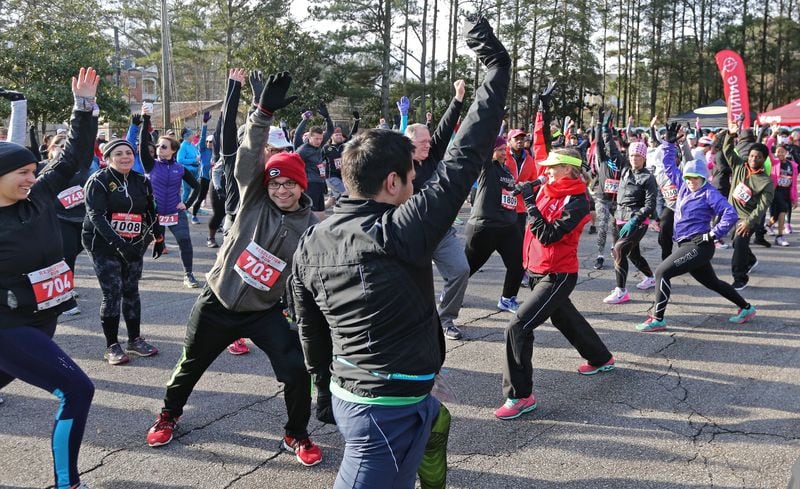 RESOLUTION TIME--Jan. 1, 2016 - Atlanta - Amy Begley (center right, in red), a coach at the Atlanta Track Club, leads runners through warm up exercises before the race. Begley was a member of the 2008 U.S. Olympic team in the 10,000 meter run. The Atlanta Track Club's Resolution Run took place New Year's morning in Brookhaven. With a 10 a.m. start time, the Resolution Run allows participants to ring in the New Year at midnight and still get some sleep before toeing the line. BOB ANDRES / BANDRES@AJC.COM