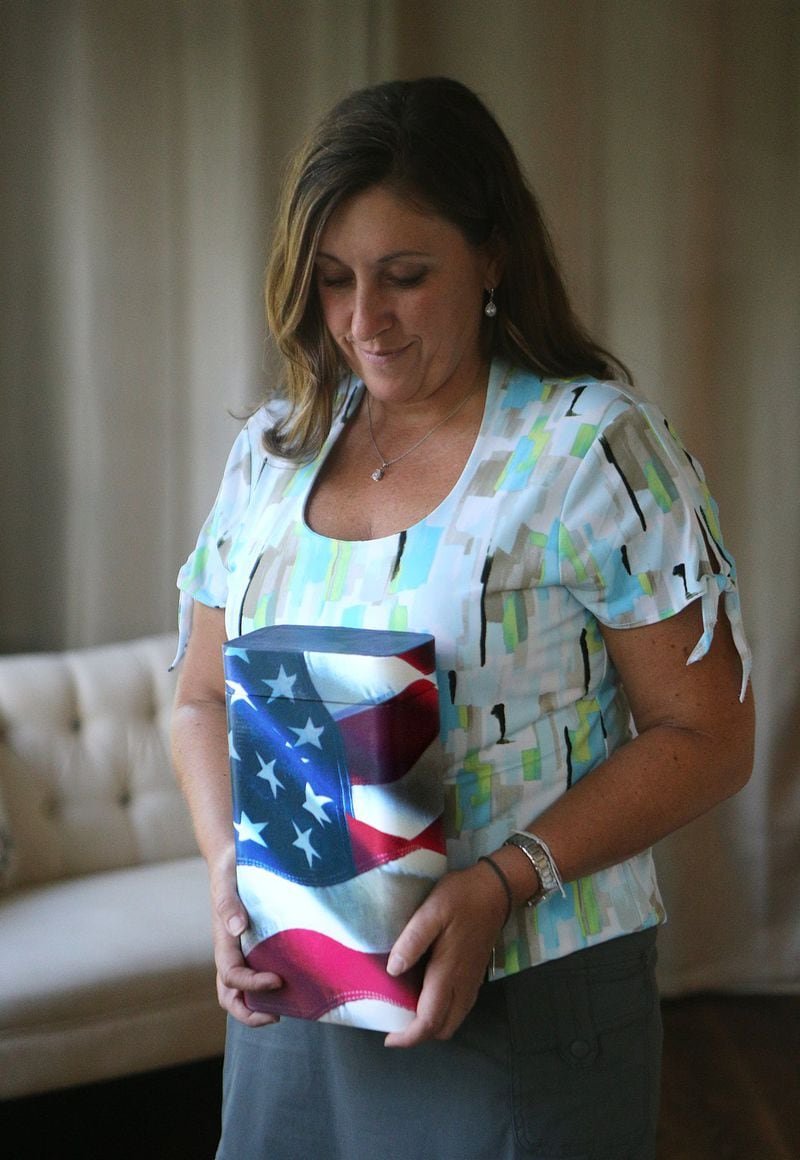 Amanda holds her father’s urn. She carries the ashes in velvet bags when they go on trips. CURTIS COMPTON/CCOMPTON@AJC.COM