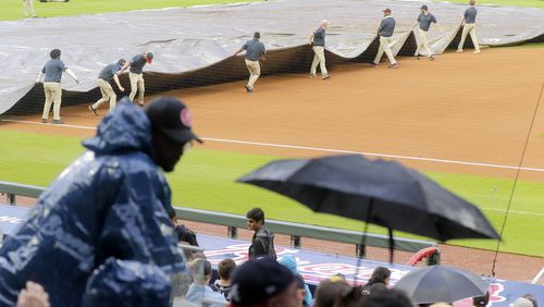 Fans wait as the field is covered for a second time as rain starts before a baseball game between the Atlanta Braves and the San Diego Padres at Trust Park in Atlanta on Monday, July 19, 2021. The game was later postponed and rescheduled as part of a day-night doubleheader on Wednesday.